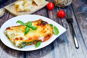   Delicious Home made Lasagna  with minced meat,tomato sauce and spinach  on a wooden rustic  background.Home made italian meal