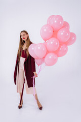 stylish young girl in burgundy clothes and pink balloons on a white background