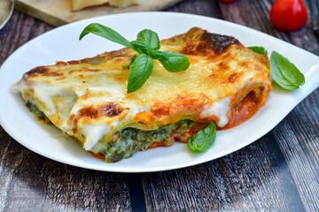  Delicious Home made Lasagna  with minced meat,tomato sauce and spinach  on a wooden rustic  background.Home made italian meal