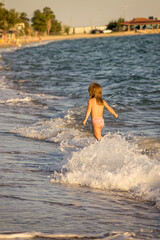 little girl runs in the shallows