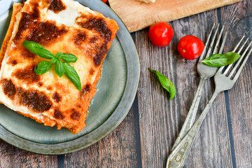   Delicious Home made Lasagna bolognese  with minced meat,tomato sauce and spinach  on a wooden rustic  background.Home made italian meal