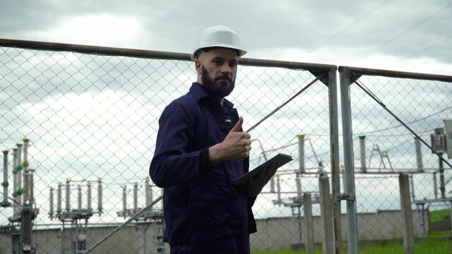 Engineer working near near power station. Male monitoring system performance and making notes in program