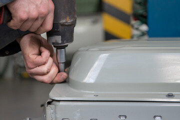 Worker removes upper case of high voltage battery pack using pneumatic power wrench; part of seria