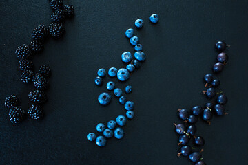 Mix set layout of different types of black berries on a black table. Stylish seasonal vitamins