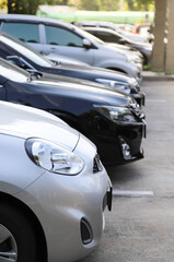Naklejka premium Closeup of front side of bronze car with other cars parking in outdoor parking area. Vertical view.
