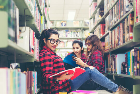 Group asian women in library reading something in a book and choosing a book in a library. Education Concept