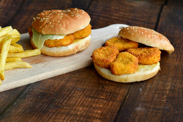 Home made  spicy crispy chicken burger and french fries on wooden table isolated on dark background.