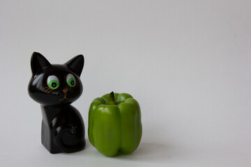 black toy cat and green pepper isolated on white