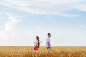 Fototapeta na wymiar Man and woman standing back to each other in wheat field. Quarrel and misunderstanding in family