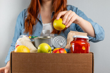 Woman packing a donation box with food items for people in isolation