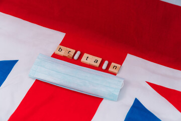 Fototapeta na wymiar Mixed pills with blue protective mask on UK flag with the inscription Britain. UK healthcare. Covid-19 protective