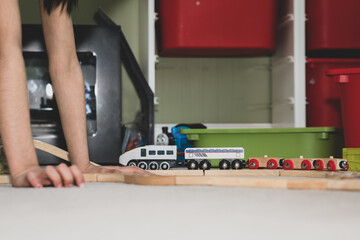 School age children building a wooden toy train track at home on the carpet. 