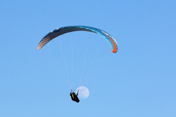 Paraglider flying wing in a blue sky with the moon	