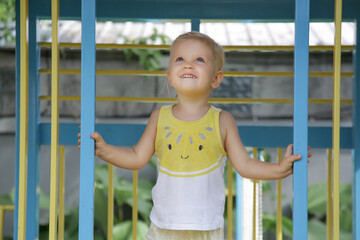 Fototapeta premium Active toddler girl playing on outdoor playground. Healthy summer activity for children. Kid playing on school or kindergarten yard. 