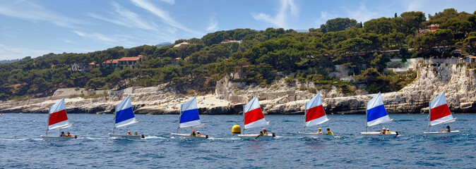 A flotilla of small boats with colourful sails on the Mediterranean Sea near Marseille, France.