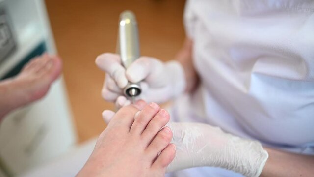 Hardware medical pedicure with nail file drill apparatus. Patient on pedicure treatment with pediatrician chiropodist. Foot peeling treatment at spa with a special device. Clinic of Podiatry Podology.