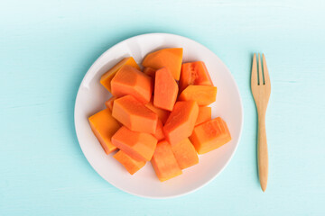 Sliced ripe papaya fruit on plate and fork on pastel color background, Tropical fruit