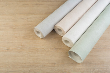 rolls of multi-colored paper wallpaper on a wooden table