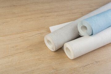 rolls of multi-colored paper wallpaper on a wooden table