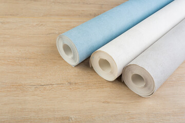 rolls of multi-colored paper wallpaper on a wooden table