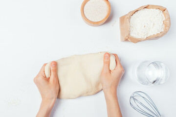 Flat lay female hands kneading dough on white table