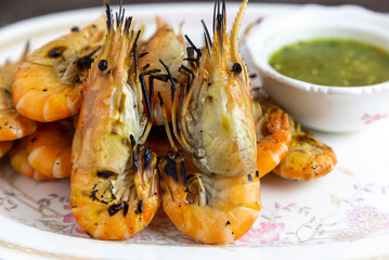 Grilled shrimp and a dipping sauce bowl placed on a plate
