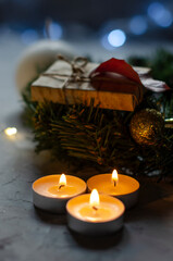 Christmas, New Year's gifts are packed in kraft paper on a table with candles and a Christmas wreath