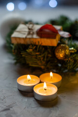 Christmas, New Year's gifts are packed in kraft paper on a table with candles and a Christmas wreath
