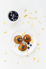 Homemade muffins with blueberries without gluten, lactose and sugar on a white plate. Vertical orientation, top view.