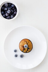 Homemade muffins with blueberries and coconut gluten free, lactose and sugar on a white plate. Vertical orientation, top view.