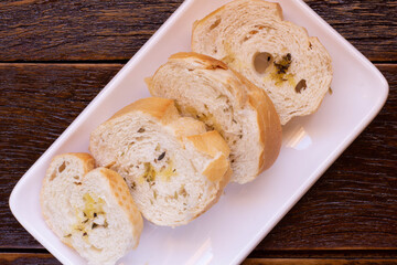 White dish with toasted bread on wooden background.