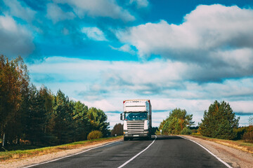 White Truck Or Tractor Unit, Prime Mover, Traction Unit In Motion On Summer Road, Freeway. Asphalt Motorway Highway During Sunny Day. Business Transportation And Trucking Industry Concept.