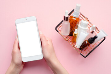 Buy cosmetics online concept. Female hands holding mobile phone with blank screen mockup and...