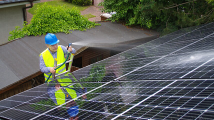 Man cleans solar panel on the roof - maintenance of renewable energy in a private home