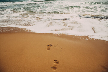 Fototapeta na wymiar Two Human Footprints On Sand Beach In Beautiful Sunny Summer Day. Beauty In Nature