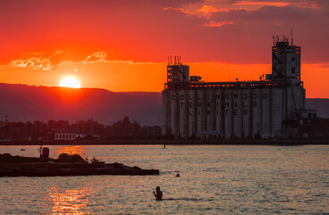 Sunset behind Collingwood Terminals and Blue Mountain with swimmers in lake