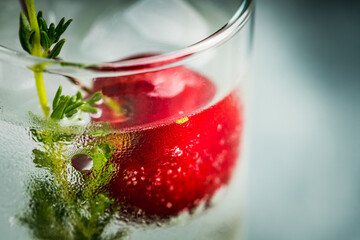 Gin based cocktail with cherries and thyme herbs on the rustic background. Selective focus. Shallow depth of field. 