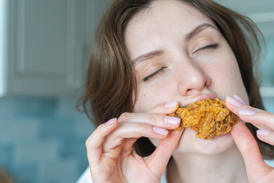 Unhealthy overeating. A woman bites chicken nuggets, close-up. Junk food