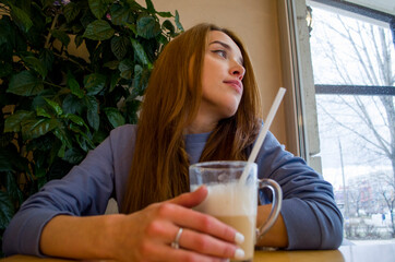 A girl is drinking coffee in a coffee house.

