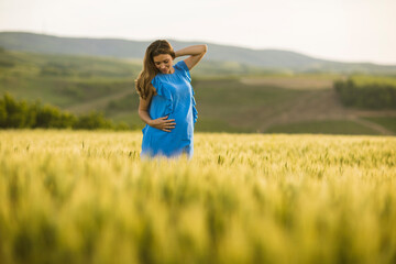 Naklejka na ściany i meble Young pregnant woman in the field
