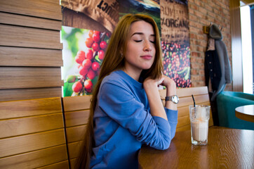 A girl is drinking coffee in a coffee house.

