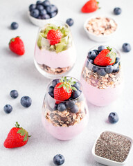Chia seeds pudding with granola, blueberry and strawberry in glasses. Yogurt with chia seeds, berries, kiwi and muesli for healthy breakfast, copy space