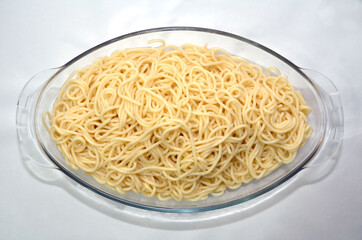 Cooked macaroni in a white bowl . Uncooked fusilli pasta in glass bowl isolated on white background...