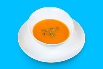 Pumpkin cream soup with seeds isolated on a blue background