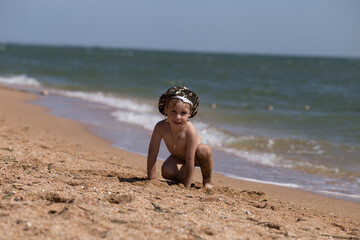 a small child plays on the beach near the sea