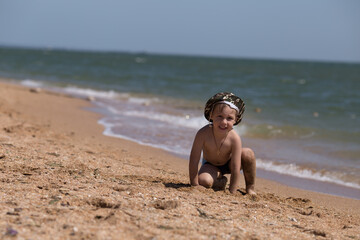 a small child plays on the beach near the sea