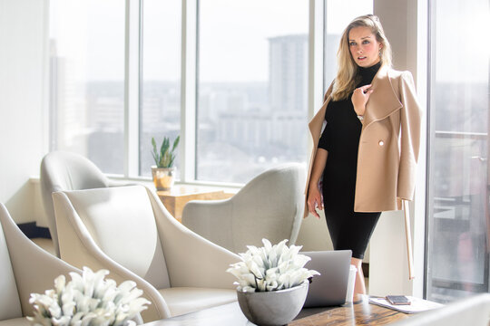 Stylish and elegant, sophisticated professional woman in business attire outfit posing in luxurious workspace lobby with city view with buildings