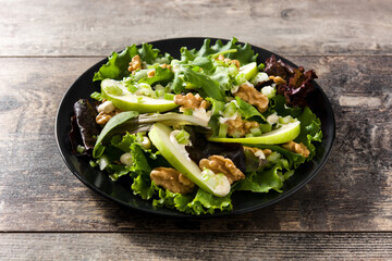 Fresh Waldorf salad with lettuce, green apples, walnuts and celery on wooden table.	