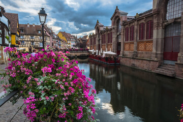 Fototapeta na wymiar The beautiful navigable canal of Colmar, in Alsace, France covered in its margins and its bridges, with flowers,