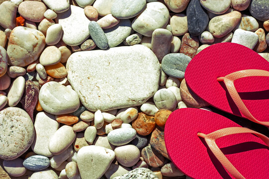 Pink flip flops on the pabble beach. Summertime sea holiday concept. Top view. Copy space